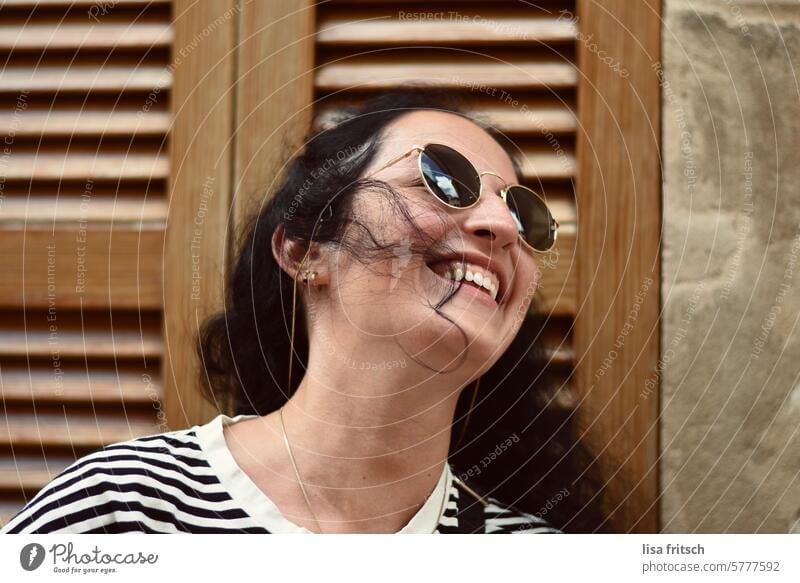 LÄCHELNDE FRAU - HAARE IM GESICHT - Frau schwarze haare Locken Sonnenbrille lachen freudig Wegsehen hübsch Haare im Gesicht windig Sommer Urlaub genießen Zeit