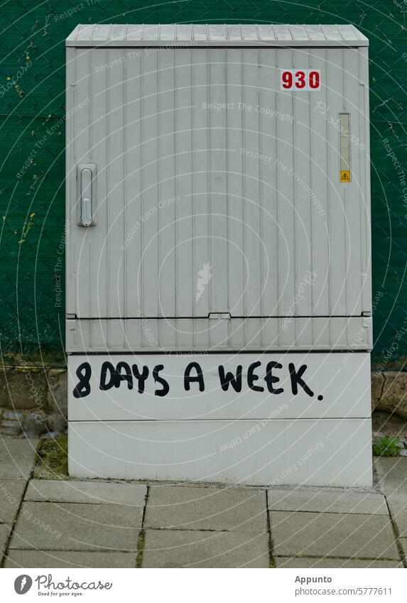 Ruhelos "8 DAYS A WEEK" - Schriftzug in schwarzen Großbuchstaben auf dem Sockel eines hellgrauen Elektroverteilerkastens (Schaltschrank) im Außenbereich am Rande eines Bürgersteigs