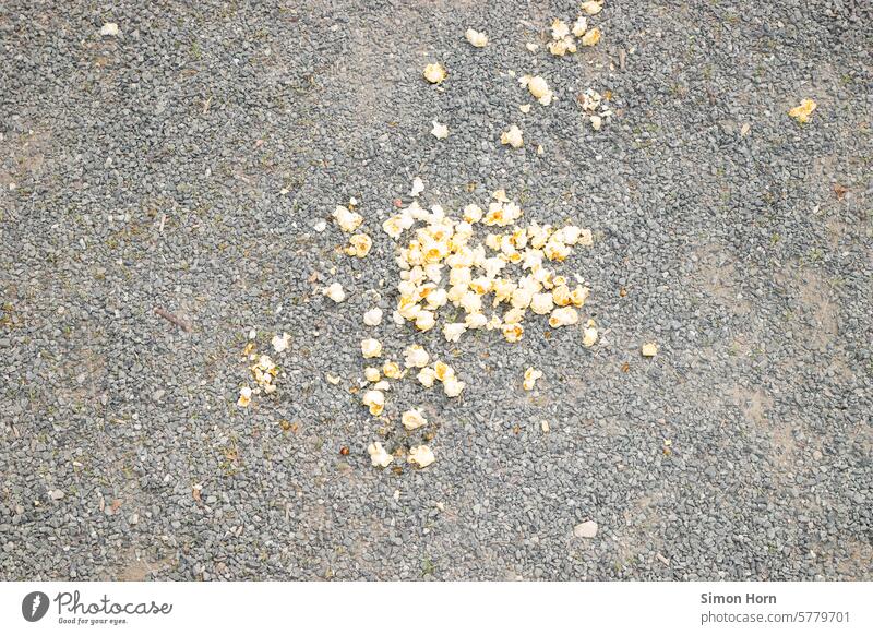 Popcorn liegt auf einem Schotterboden auf den Boden gefallen heruntergefallen Kieselsteine verteilt ungeschickt aus Versehen verschütten verlieren Lebensmittel