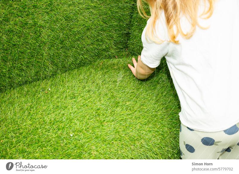 Kind fühlt die Struktur von Rasenflächen, die das Kind in ungewöhnlicher Komposition waagerecht und senkrecht umgeben fühlen Wiese tasten geformt Formen Flächen