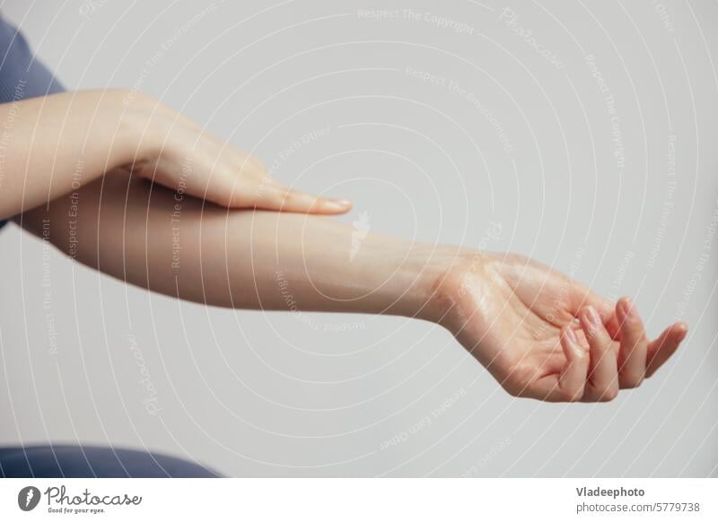 Die Frau macht eine Geste, indem sie ihren Arm mit der Hand berührt Streicheln Gel Kosmetik Gefühl Feuchtigkeit Haut Pflege Fingernagel Wärme verwöhnend