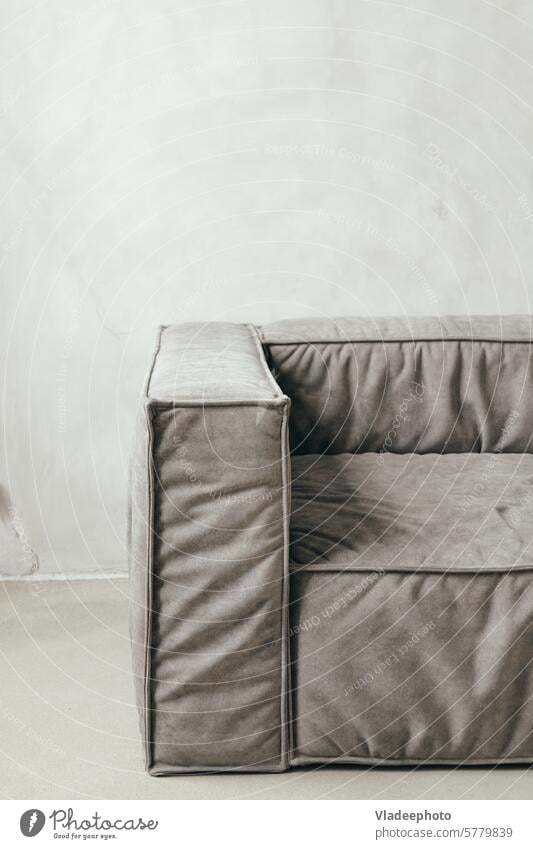 Nahaufnahme moderne Couch mit grauer Polsterung und bequemer Armlehne vor einfachem Wandhintergrund heimwärts Sofa Liege Innenbereich lebend Möbel Raum Gewebe
