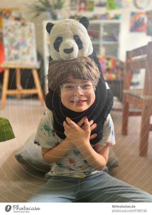 Kind mit einem Panda Kuscheltier Junge Schulkind Porträt im Innenbereich Zufriedenheit natürlich zufrieden Wohnzimmer Kreativität pädagogik Erziehung Mensch