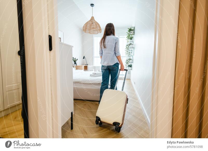 Rückansicht einer jungen Frau, die mit ihrem Gepäck ein Hotelzimmer betritt Koffer Verpackung Bekleidung Ferien reisen Vorbereitung Menschen eine Person Tasche