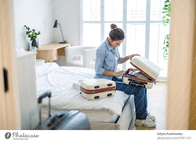 Junge Frau beim Kofferpacken im Schlafzimmer, Vorbereitung auf die Reise Verpackung Bekleidung Ferien reisen Menschen Gepäck eine Person Tasche Tourismus