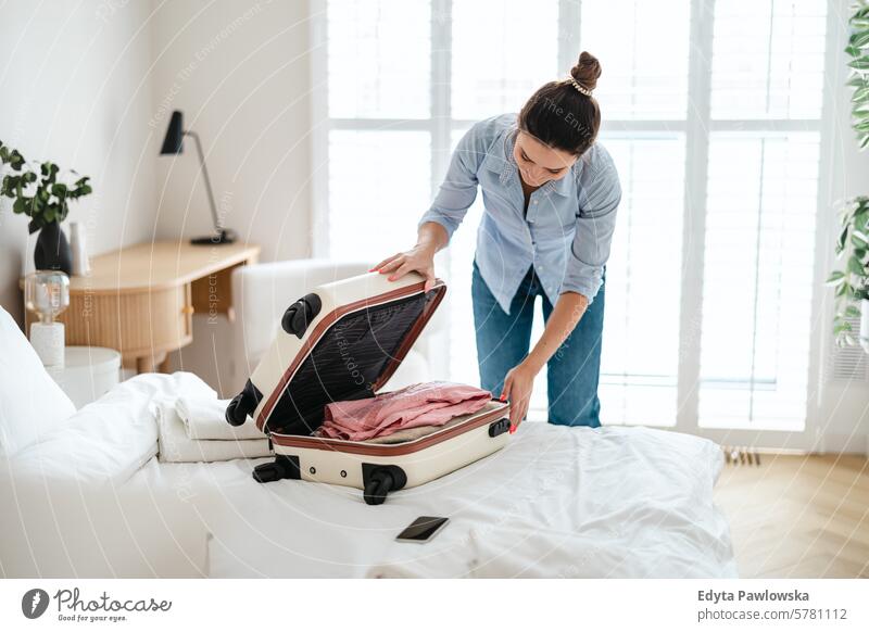 Junge Frau beim Kofferpacken im Schlafzimmer, Vorbereitung auf die Reise Verpackung Bekleidung Ferien reisen Menschen Gepäck eine Person Tasche Tourismus