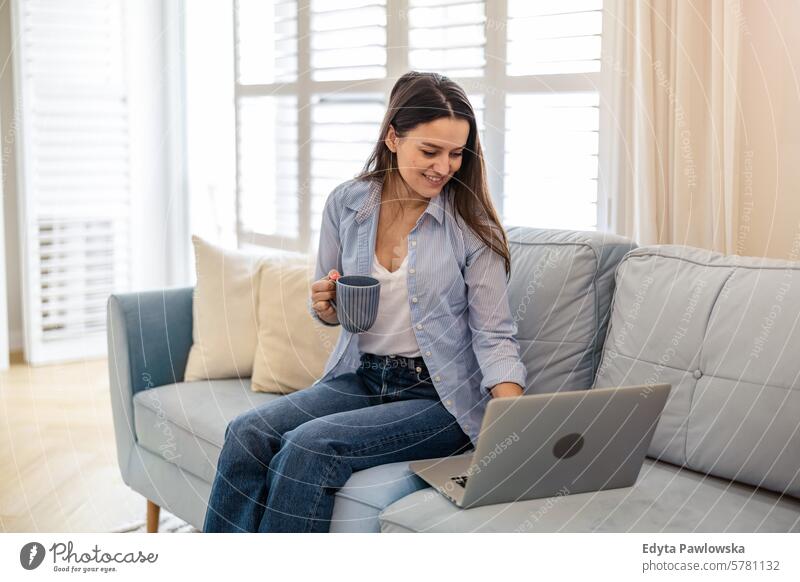 Junge Frau, die zu Hause am Laptop arbeitet Menschen eine Person Raum Wohnzimmer Erwachsener jung junger Erwachsener im Innenbereich Appartement Lifestyle Glück