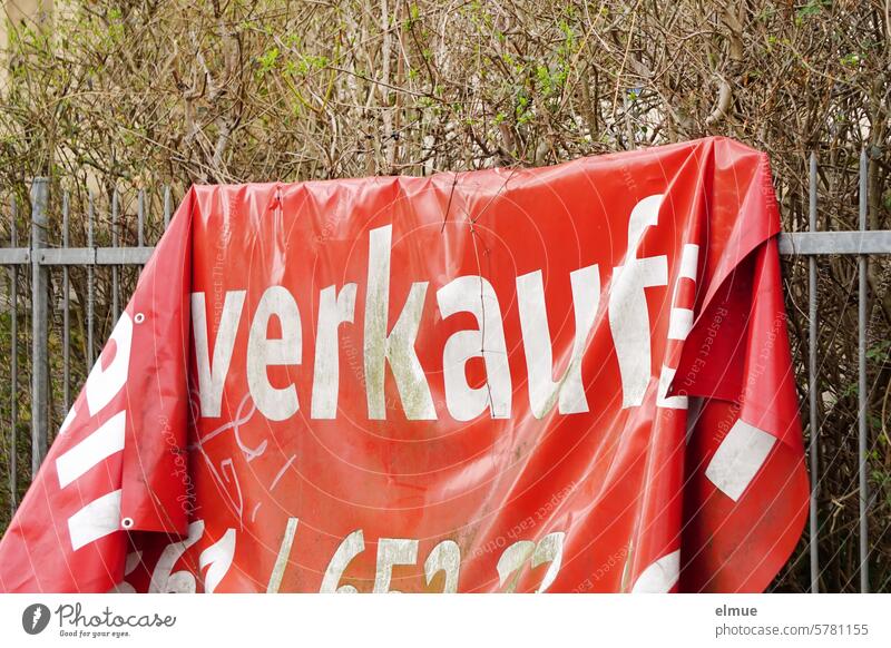 in Falten an einem Metallzaun hängendes rotes PVC Werbebanner mit der Aufschrift - zu verkaufen - Banner Angebot Offerte Immobilienverkauf Vertrieb Entgelt Blog