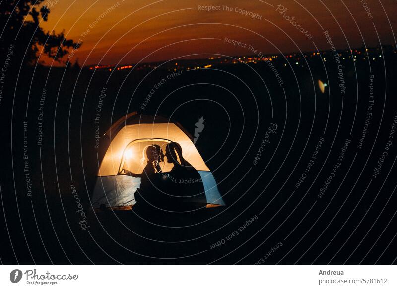 Ein junges Pärchen, ein Mann und ein Mädchen mit hellen Strickmützen, hielt an einem Camping Paar Typ Vollbart Hüte gestrickt Wärme Zelt Freudenfeuer Liebe