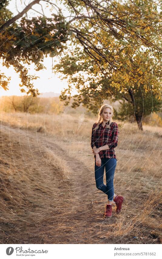 Blondine mit Zöpfen im Hemd, Jeans, rote Schuhe lächelnd blond Mädchen lacht Boden Gras Sonnenuntergang Herbst Sommer Winter Jeanshose Stiefel Zopf Bild Model