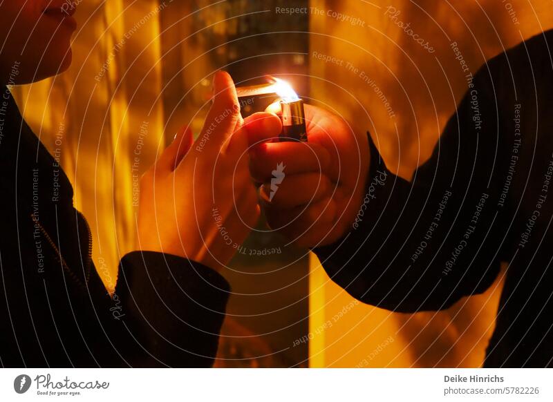 Nachtaufnahme junger Menschen im Anschnitt: eine Hand gibt der anderen Feuer mit Feuerzeug Feuer geben Zigarette rauchen anzünden nikotin Junges Fräulein paar