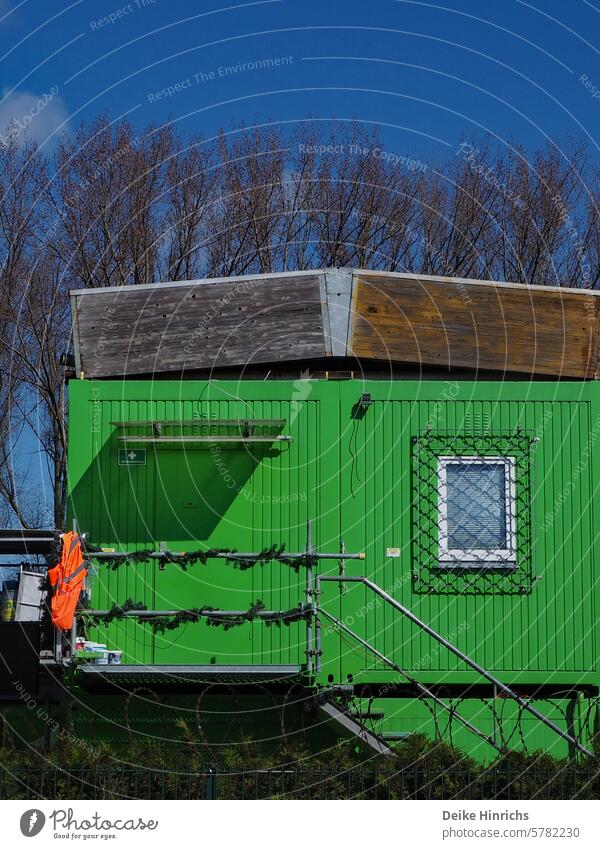 Verschlossener grüner Baucontainer mit Warnweste am Geländer vor blauem Himmel bauwesen Container safheit sicherheitsweste Grün Feierabend Außenaufnahme