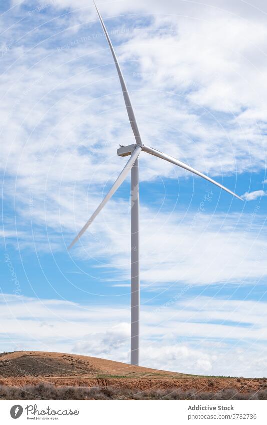Nachhaltige Windenergie in einer ländlichen Landschaft Windkraftanlage nachhaltige Energie bewölkter Himmel blau Hügel unfruchtbar umweltfreundlich
