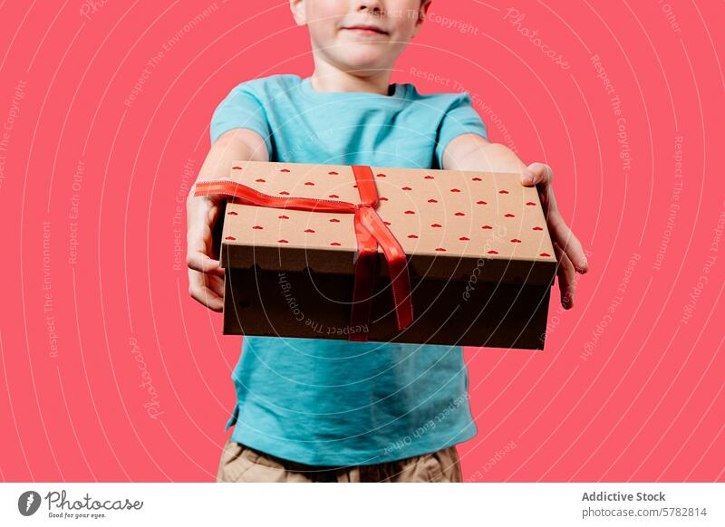 Junge bietet stolz eine Geschenkbox mit Herzmotiv an Kasten Bändchen Muster Geben heiter präsentieren Freundlichkeit rot symbolisieren Kind Halt Angebot Feier