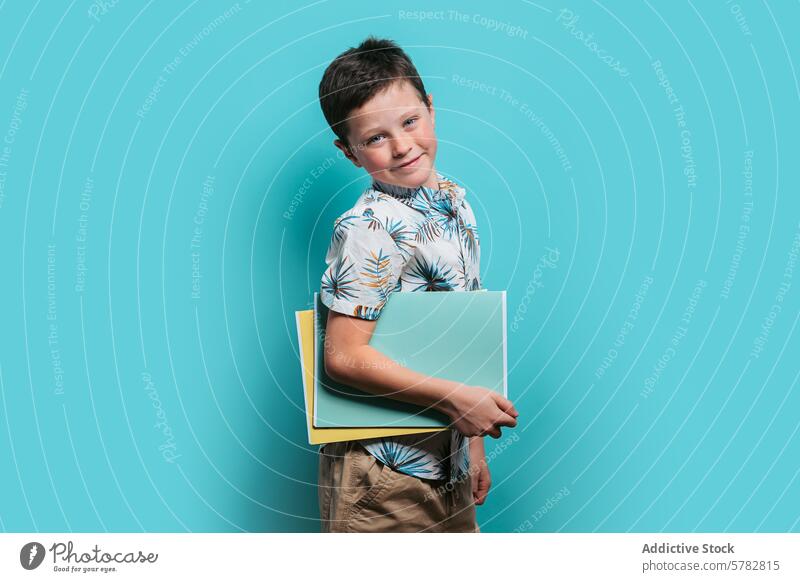 Lächelnder Junge mit Ordnern auf türkisem Hintergrund Mappe tropisch Hemd jung heiter Bildung Schüler entspannt pulsierend lässig Beteiligung Porträt Atelier