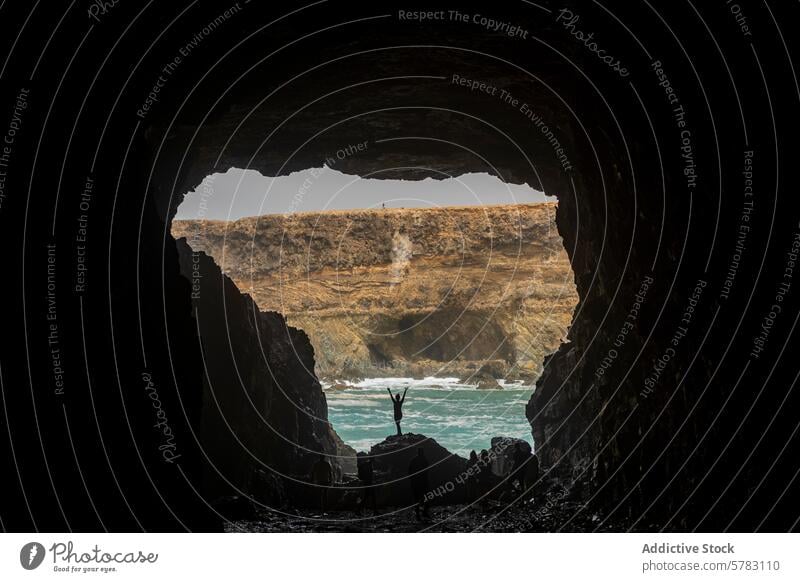 Anonyme Frau feiert das Abenteuer in der Höhle von Fuerteventura Silhouette Feier wandern Camping Kanarische Insel Spanien Küste robust angehobene Arme Natur