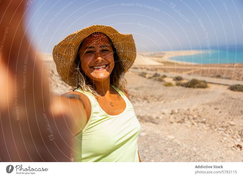Lächelnde Frau macht ein Selfie beim Wandern auf Fuerteventura wandern Kanarische Inseln Spanien Camping Strohhut sonnig heiter unwegsames Gelände Abenteuer