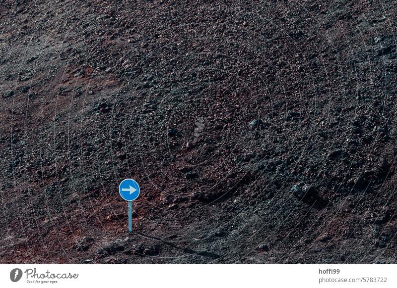 kleines richtungsweisendes Verkehrsschild in der Wildnis vor dunklem  vulkanischem Geröll richtungweisend Verkehrswege Verkehrszeichen Pfeil Außenaufnahme