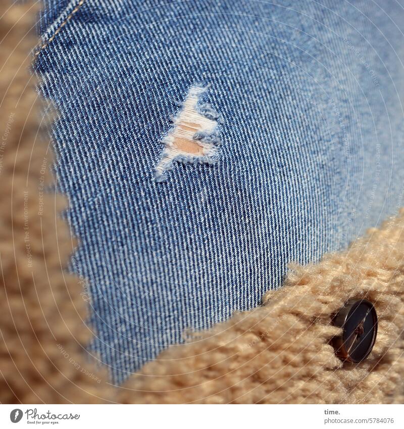 Loch in Jeans unter Flauschmantel mit Knopf stylish modisch kaputt Oberschenkel Hose sonnig Detailaufnahme Haut Riss