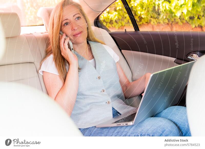 Geschäftsfrau beim Multitasking im Auto mit Telefon und Laptop Frau PKW Rücksitz Erwachsener Gespräch arbeiten Mobile Technik & Technologie professionell