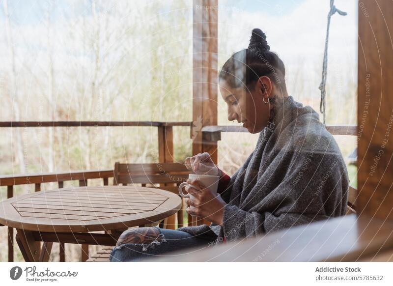 Gelassener Moment einer Frau, die auf einer Veranda Kaffee genießt Natur ruhig Gelassenheit Decke gemütlich hölzern schlürfend Erholung Morgen Windstille