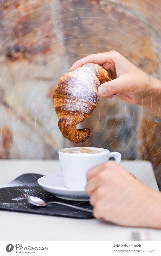 Eine abgeschnittene, nicht erkennbare Person, die einen kolumbianischen Kaffee und ein hausgemachtes Croissant-Frühstück genießt selbstgemacht Gebäck