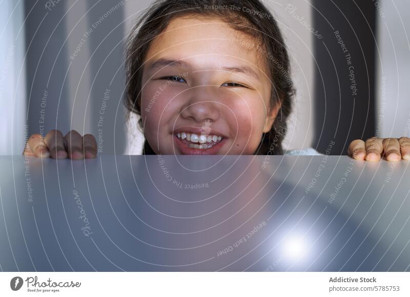 Lächelndes junges Mädchen, das über eine glänzende Oberfläche blickt guckend Nahaufnahme heiter Jugend Glück Ausdruck Positivität Kind Gesicht Zähne