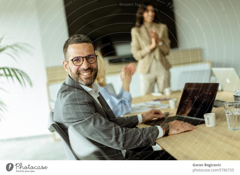 Ein lächelnder Geschäftsmann in einem modernen Büro, der eine Teambesprechung während der Arbeitszeit genießt Lächeln Sitzung Kollegen Zusammenarbeit Brille