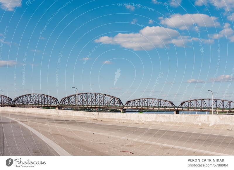 Dieses fesselnde Bild zeigt eine Eisenbahnbrücke, die einen ruhigen Fluss in Kentucky, USA, überspannt. Die Stahlkonstruktion der Brücke kontrastiert mit dem ruhigen Wasser und dem üppigen Grün und schafft eine Szene von industrieller Schönheit und natürlicher Pracht.
