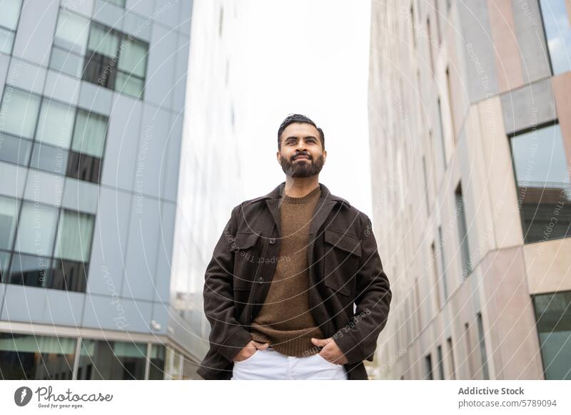 Selbstbewusster urbaner Mann in legerer Kleidung vor Gebäuden selbstbewusst lässig Mode stylisch braun Jacke Pullover im Freien modern Architektur Großstadt