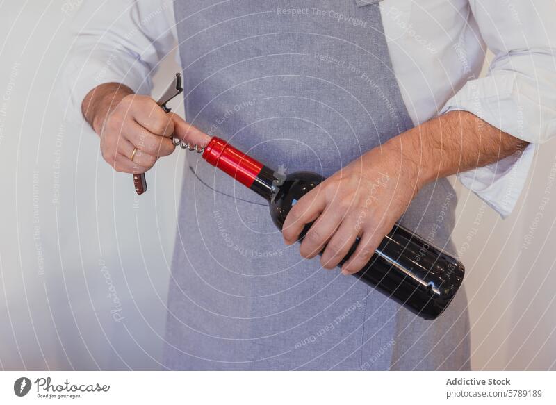 Vorbereitungen zum Entkorken einer Flasche Wein Person entkorken Korkenzieher Schürze grau rot Weinprobe Traube Getränk Alkohol trinken Weingut Weinflasche