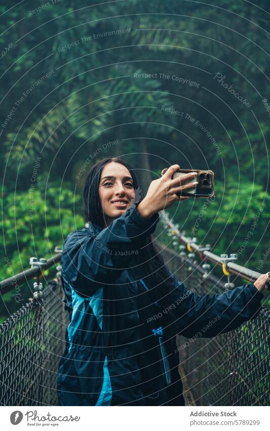 Frau, die ein Selfie auf einer Hängebrücke in Costa Rica macht Kettenbrücke Dschungel reisen Abenteuer Smartphone Fotografie Tourist Natur tropisch Wald