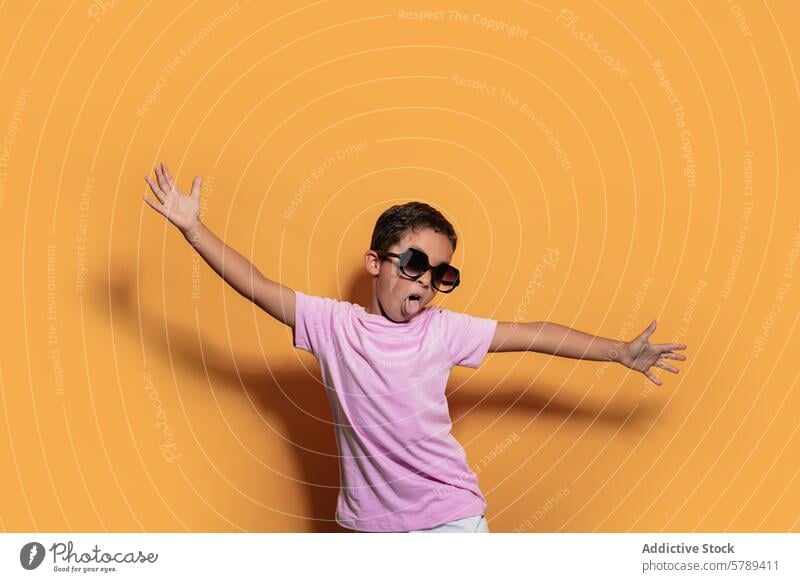 Energetischer Junge posiert mit Sonnenbrille vor einem gelben Hintergrund Kind Atelier Pose überdimensioniert spielerisch Energie Spaß freudig jung hell Farbe