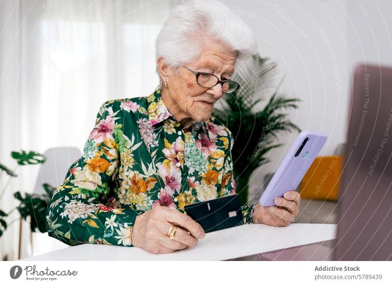 Ältere Frau verwaltet ihre Finanzen zu Hause älter Smartphone Kreditkarte heimwärts Blumenhemd Verwalten im Innenbereich Senior Technik & Technologie