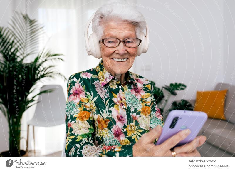 Ältere Frau genießt Musik zu Hause mit Smartphone Senior älter Kopfhörer heimwärts heiter weiße Haare Glück Technik & Technologie modern Freizeit Lächeln