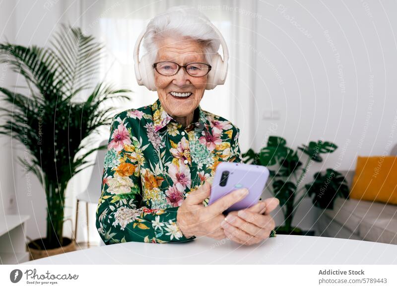 Ältere Frau genießt Musik zu Hause mit Smartphone Senior älter Kopfhörer heimwärts heiter weiße Haare Glück Technik & Technologie modern Freizeit Lächeln