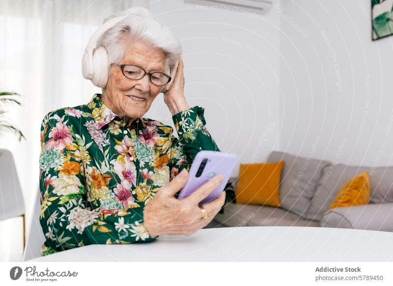 Ältere Frau genießt Musik und Technik zu Hause Senior älter Kopfhörer Smartphone Technik & Technologie freudig weiße Haare Brille im Innenbereich sitzend bequem