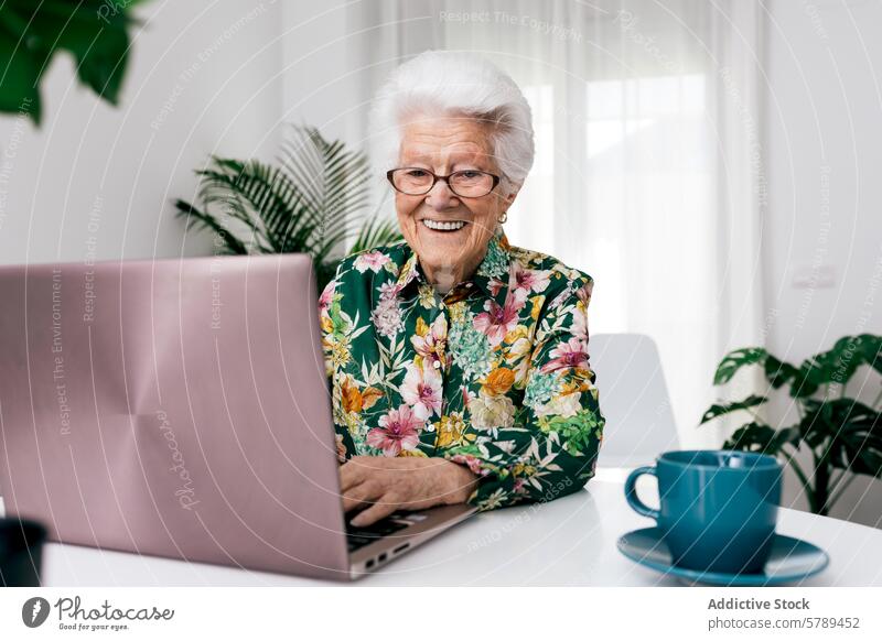 Ältere Frau, die zu Hause mit einem freudigen Gesichtsausdruck einen Laptop benutzt Senior heimwärts arbeiten heiter älter Kaffee Selbstvertrauen Fröhlichkeit
