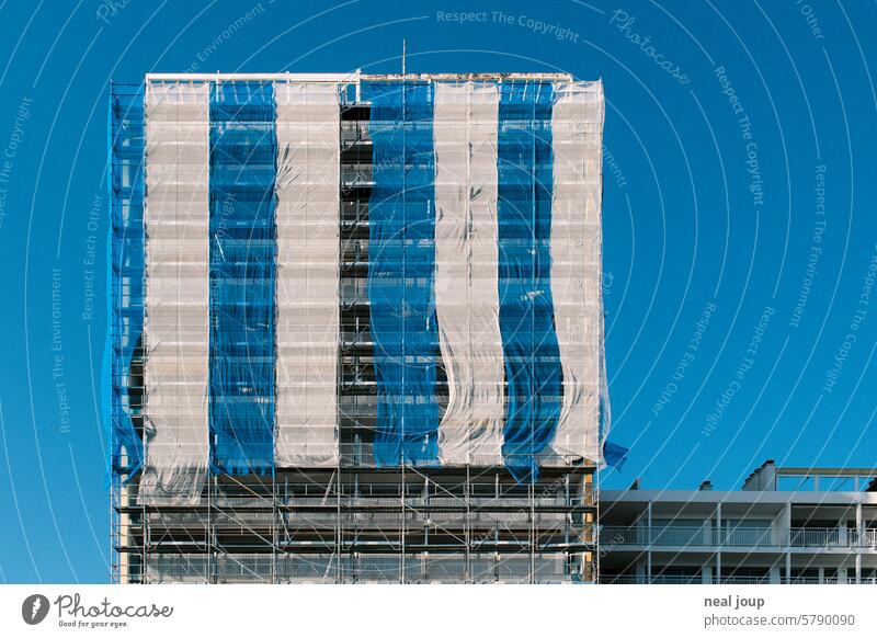 Baugerüst mit blau-weiß gestreifter Gaze verhüllt vor einem strahlend blauen Himmel Architektur Baustelle Geometrie grafisch Struktur Color Blocking Blau