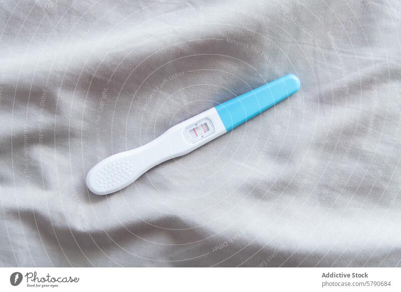 Positiver Schwangerschaftstest auf einem grauen Stoffhintergrund positives Ergebnis Mutterschaft Vorfreude Gewebe Hintergrund Prüfung medizinisch Gesundheit