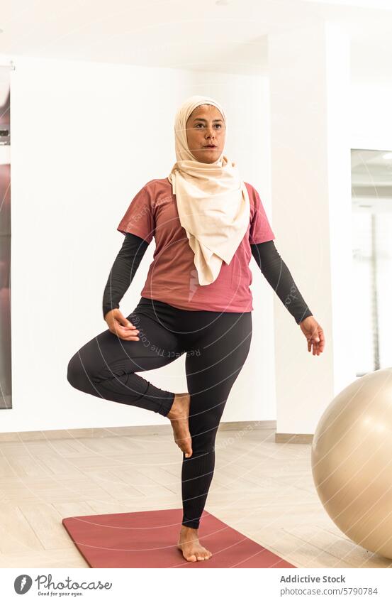 Muslimische Frau, die in der Umkleidekabine die Yoga-Pose Vrksasana übt muslimisch vrksasana Baumhaltung Umkleideraum Übung Hijab Vorbereitung Fitness