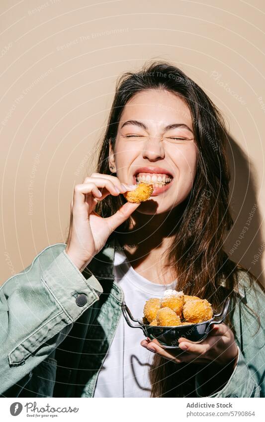Fröhliche junge Frau, die gebratene Käsebällchen genießt heiter Essen Käsekugel Snack Freude Knusprig lecker Lebensmittel Schalen & Schüsseln Vergnügen