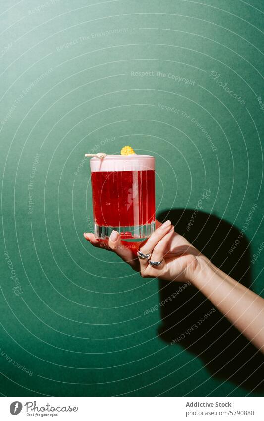 Hand mit einem Beeren-Mojito-Cocktail mit Schaum schäumen erfrischend Präsentation grüner Hintergrund trinken Alkohol Getränk Glas rot schaumig Mixologie Bar