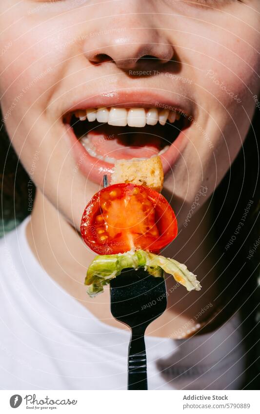 Nahaufnahme eines frischen Salatbisses auf einer Gabel, gehalten von einer lächelnden Person Salatbeilage Biss Frau Tomate Crouton Lächeln Gesundheit Snack
