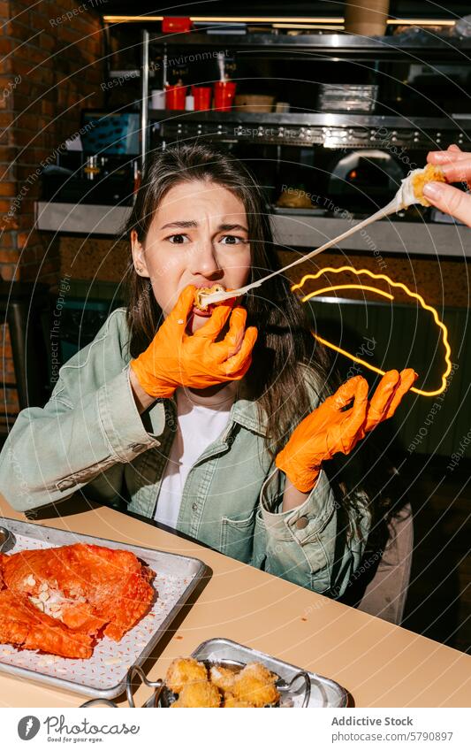 Frau genießt einen klebrigen Cheburek in einem legeren Restaurant Essen Käse zähflüssig Biss lässig speisend gebratener Mozzarella orange Handschuhe gebacken