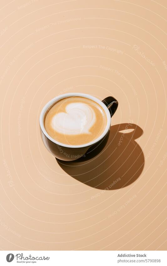 Herzförmige Latte Art auf Cappuccino in Keramiktasse Kaffee cremefarbener Hintergrund Barista Espresso melken schäumen Café Getränk Heißgetränk cremig Schatten