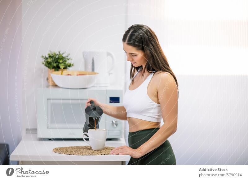 Sportliche Frau bei der Kaffeezubereitung in einer modernen Küche sportlich Fitness Gesundheit Lifestyle heimwärts Moka-Topf eingießen Becher aktiv Wohlbefinden