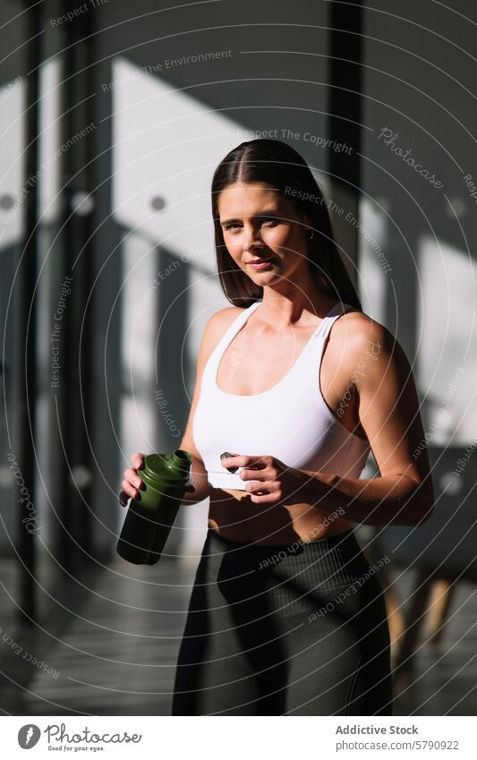 Sportliche Frau zu Hause mit Fitnessgetränk Athlet Sportbekleidung trinken Flasche Sportgetränk Gesundheit Lifestyle im Innenbereich Sportkleidung heimwärts