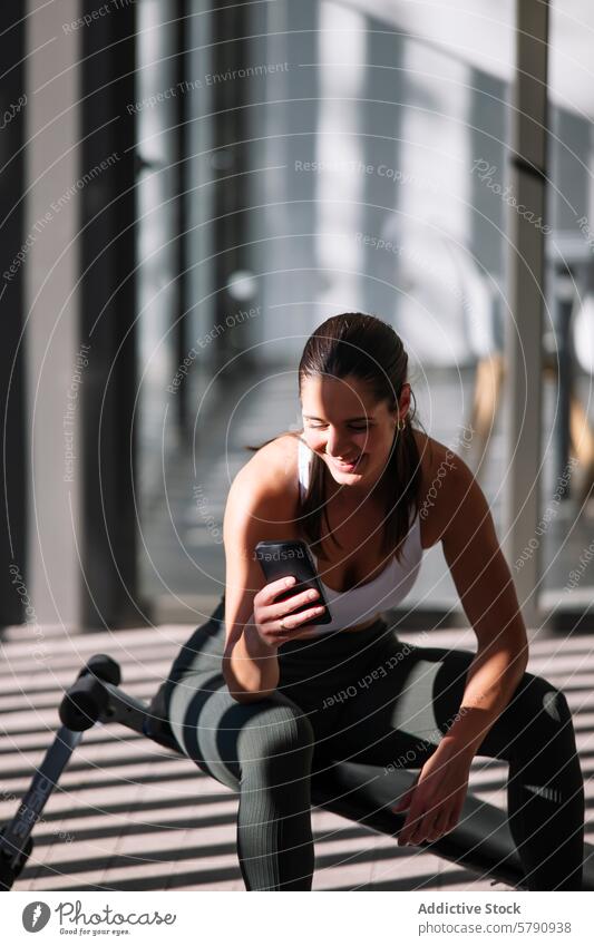 Aktive Frau nutzt Smartphone beim Training zu Hause Sportbekleidung Fitness Übung heimwärts Pause aktiv Lifestyle Morgen Sonne sportliche Freizeit
