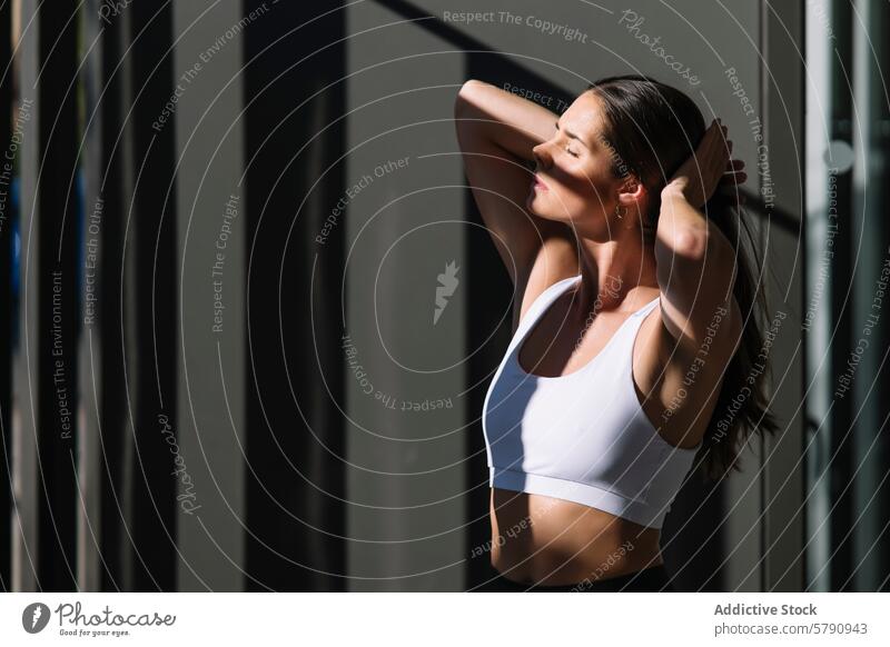 Sportliche Frau beim Dehnen zu Hause bei natürlichem Licht Fitness sportlich strecken heimwärts Sonnenlicht Sportbekleidung friedlich Erholung im Innenbereich